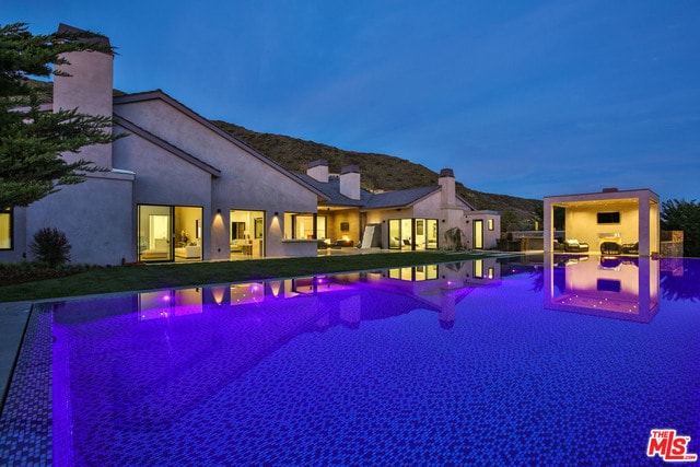 pool at dusk featuring a mountain view and a patio area