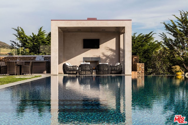 view of pool with a fireplace, a bar, a patio, and area for grilling