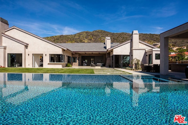 view of swimming pool featuring a mountain view, a patio area, and a yard