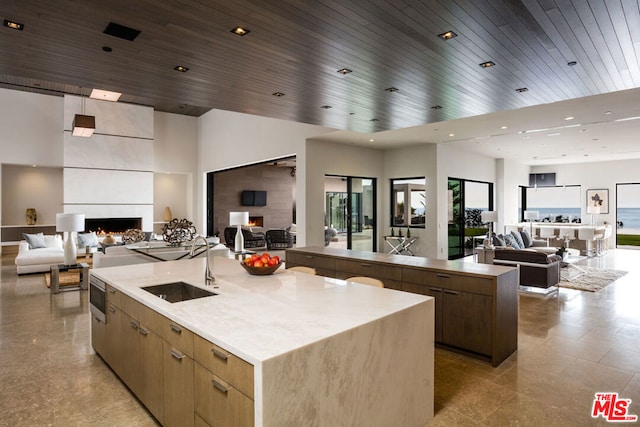 kitchen with wooden ceiling, a high ceiling, a spacious island, sink, and a fireplace