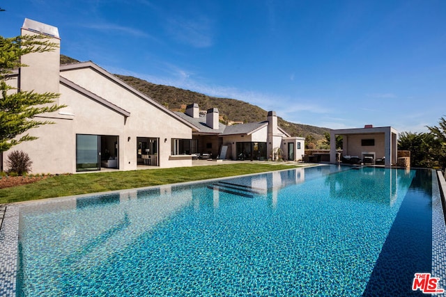 view of pool with a mountain view, a patio area, and a yard