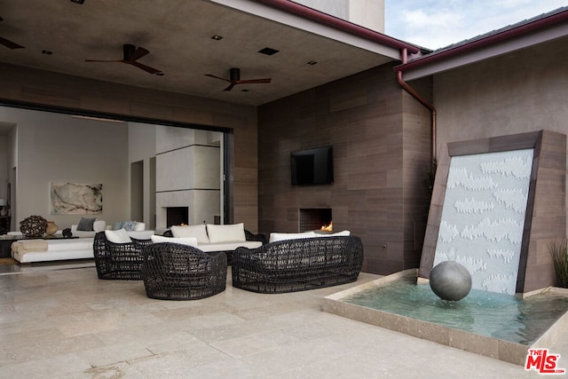 view of patio with an outdoor living space with a fireplace and ceiling fan