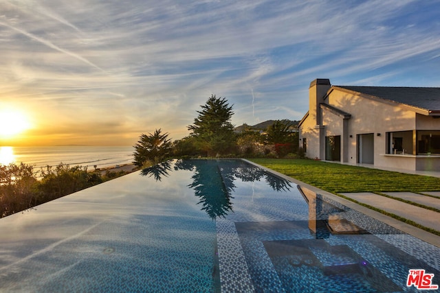 pool at dusk with a lawn and a water view