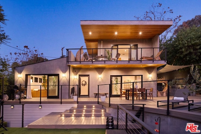 back house at dusk with a balcony