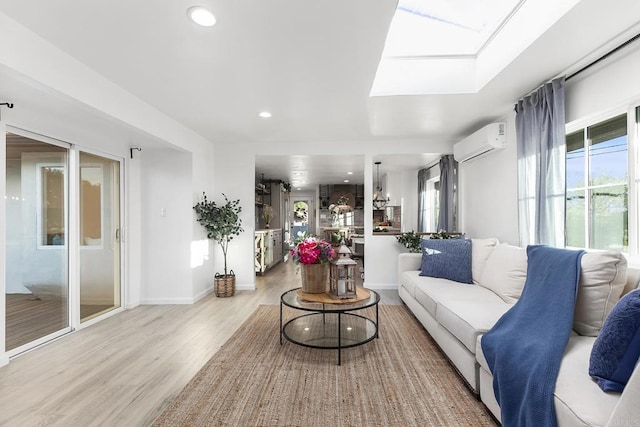 living room featuring a wall mounted AC, light hardwood / wood-style flooring, and a skylight