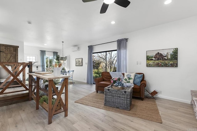 dining space featuring a wall mounted air conditioner, light hardwood / wood-style floors, and ceiling fan