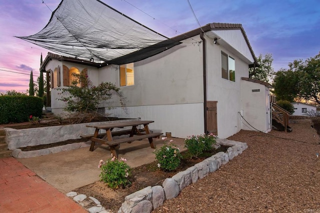 property exterior at dusk with a patio area