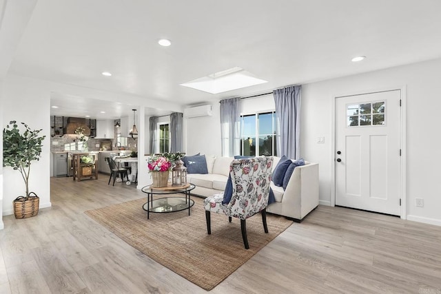 living room with a wall mounted air conditioner and light hardwood / wood-style flooring