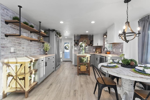 kitchen with decorative backsplash, wooden counters, pendant lighting, a notable chandelier, and white cabinets