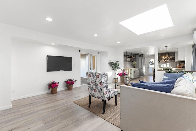 living room featuring a skylight and light hardwood / wood-style flooring