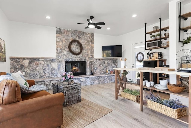 living room with ceiling fan, a fireplace, and light hardwood / wood-style floors