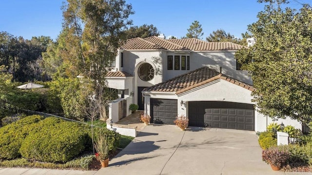 mediterranean / spanish home with stucco siding, concrete driveway, an attached garage, and a tiled roof