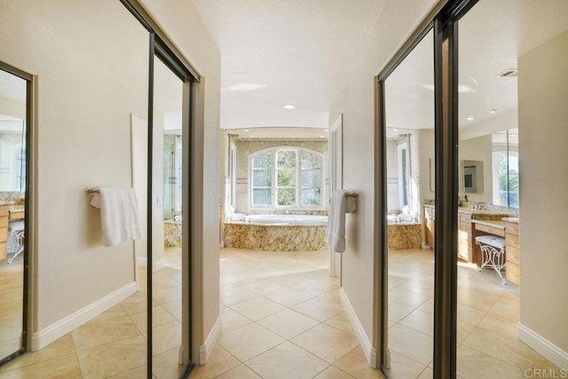 full bathroom featuring vanity, tile patterned floors, a bath, and baseboards