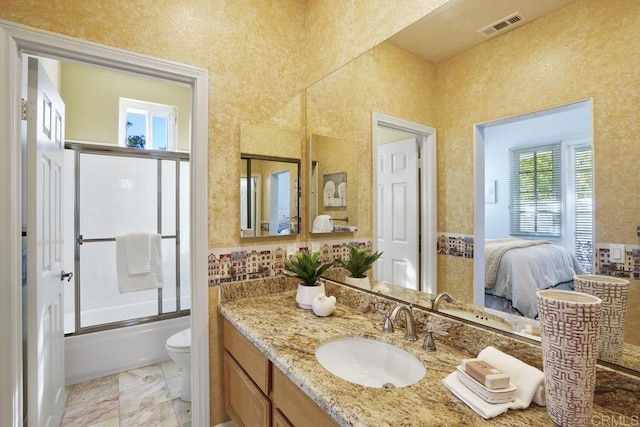 ensuite bathroom featuring visible vents, toilet, ensuite bath, combined bath / shower with glass door, and vanity