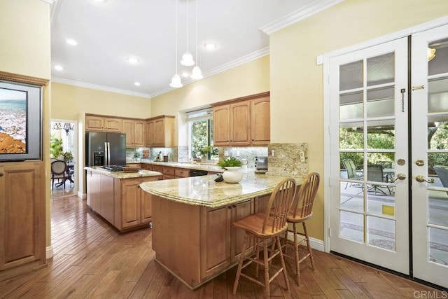 kitchen with stainless steel fridge with ice dispenser, ornamental molding, hardwood / wood-style flooring, backsplash, and a center island