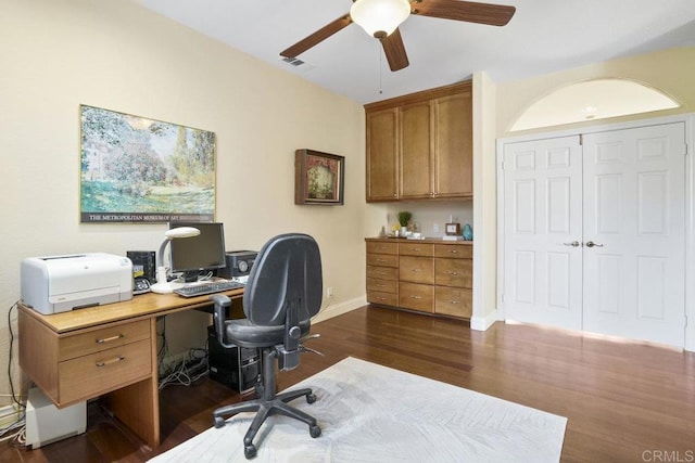 home office with a ceiling fan, dark wood-style floors, visible vents, and baseboards