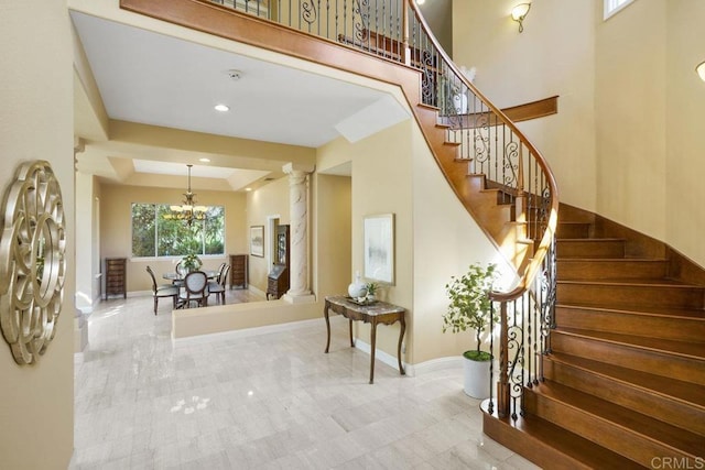 interior space with baseboards, ornate columns, a high ceiling, recessed lighting, and a notable chandelier