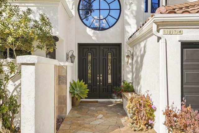 entrance to property with a tile roof and stucco siding