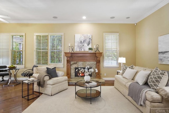 living area featuring crown molding, baseboards, hardwood / wood-style floors, recessed lighting, and a fireplace