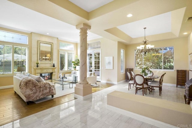 dining room featuring a chandelier, baseboards, a glass covered fireplace, and ornate columns