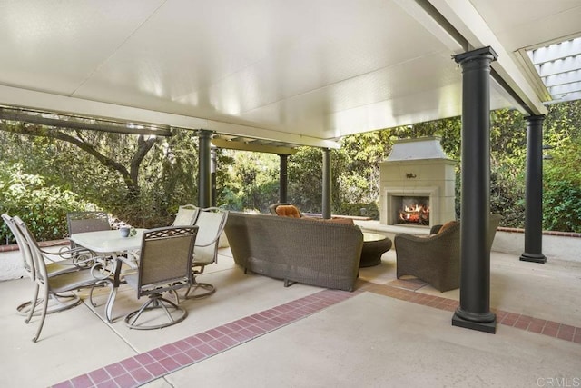 view of patio / terrace with outdoor dining area and a lit fireplace