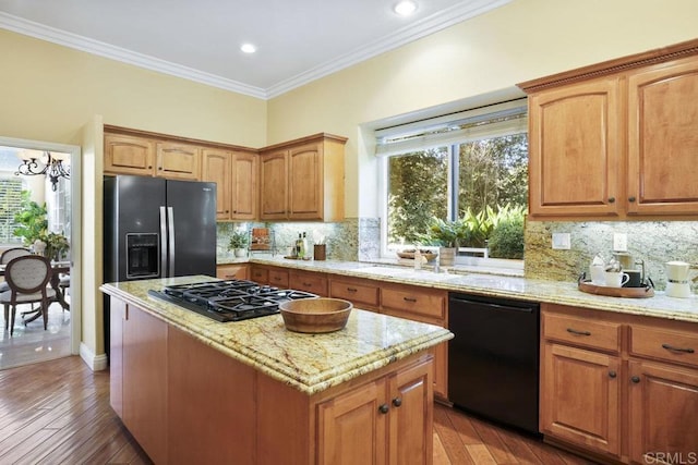 kitchen featuring ornamental molding, light stone countertops, black appliances, and a sink