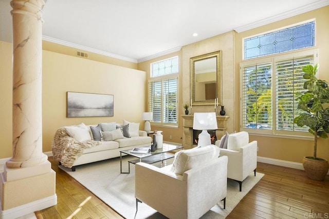 living area featuring decorative columns, visible vents, wood-type flooring, and ornamental molding