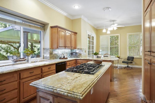 kitchen featuring black appliances, tasteful backsplash, a center island, crown molding, and light stone countertops