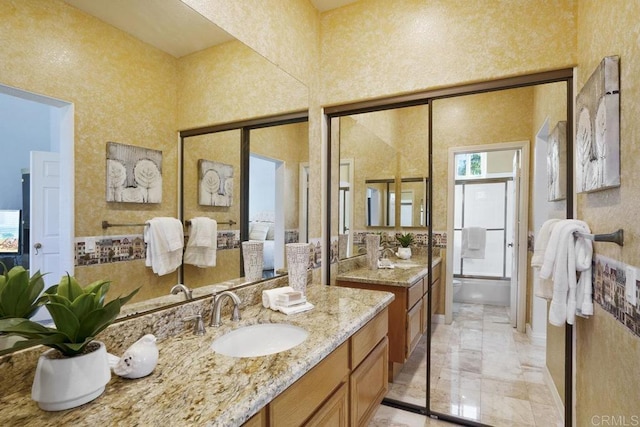 bathroom featuring a sink, a high ceiling, two vanities, and shower / washtub combination