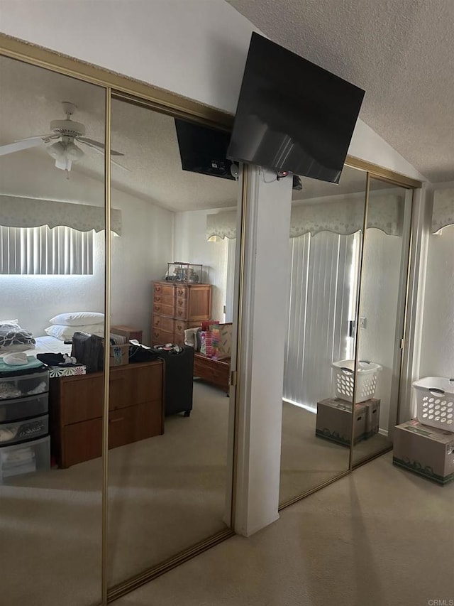 interior space with ceiling fan, a closet, a textured ceiling, and vaulted ceiling