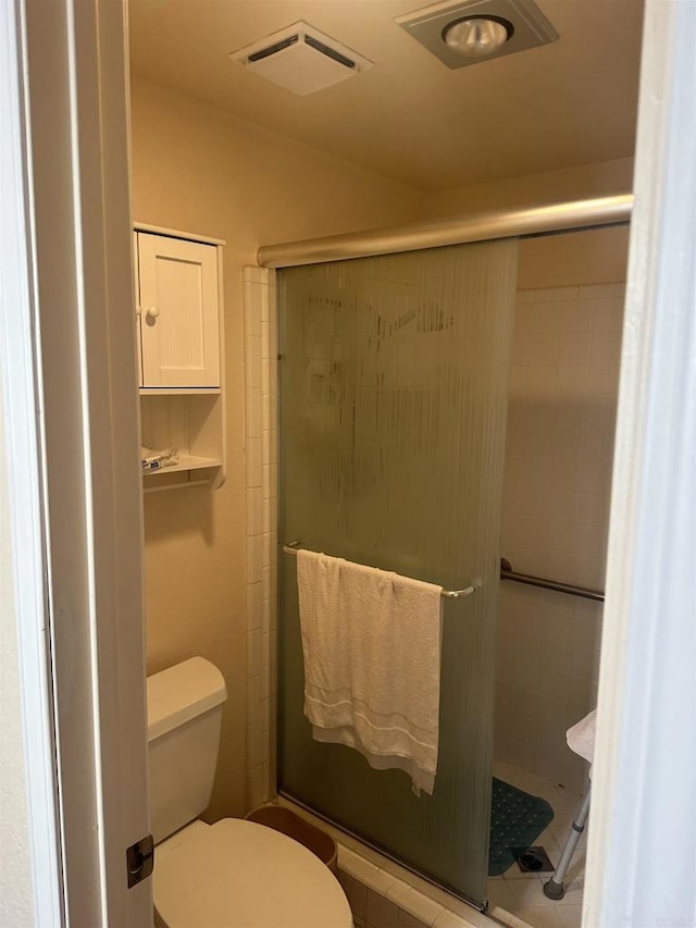 bathroom featuring toilet and a shower with shower door