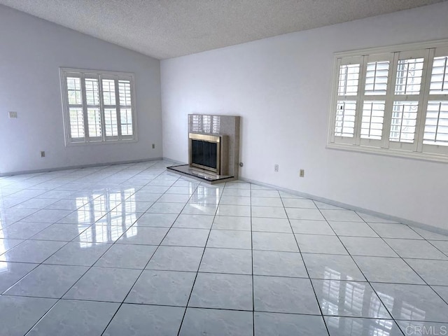 124 Palawan Way, San Diego, CA 92114 - unfurnished living room with healthy amount of natural light, tile patterned floors, vaulted ceiling, a textured ceiling, and a high end fireplace