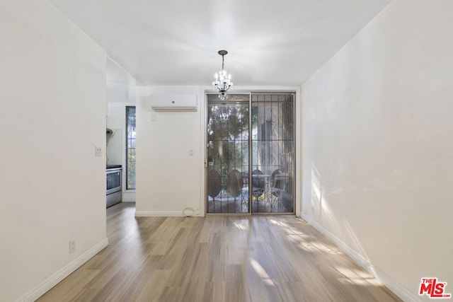 interior space with a wall unit AC, an inviting chandelier, and hardwood / wood-style flooring