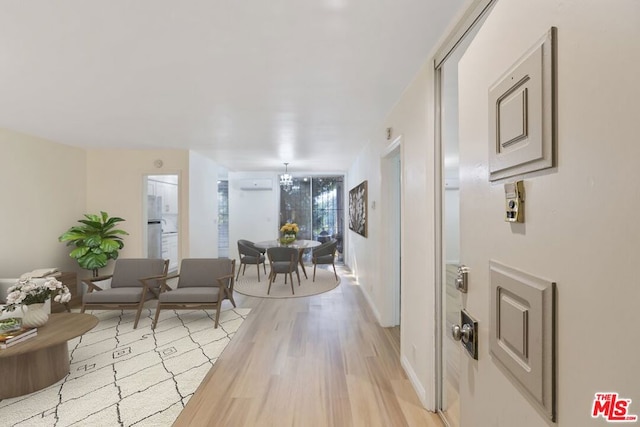 interior space featuring a wall mounted AC, light hardwood / wood-style flooring, and a chandelier