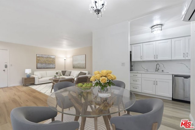 dining room with light wood-type flooring, a wall mounted AC, a notable chandelier, and sink