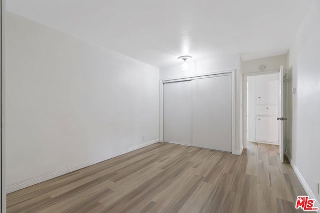 unfurnished bedroom featuring light wood-type flooring and a closet