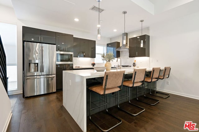 kitchen with a kitchen bar, dark hardwood / wood-style flooring, wall chimney exhaust hood, stainless steel appliances, and decorative light fixtures