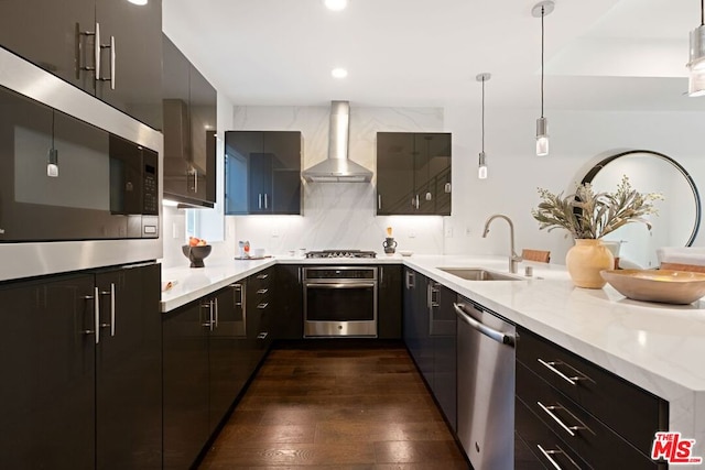 kitchen with backsplash, stainless steel appliances, sink, wall chimney range hood, and pendant lighting