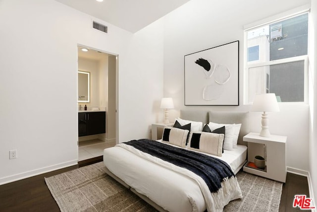 bedroom with hardwood / wood-style flooring and connected bathroom