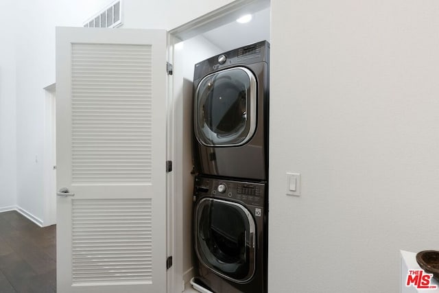 clothes washing area with dark hardwood / wood-style flooring and stacked washer / dryer