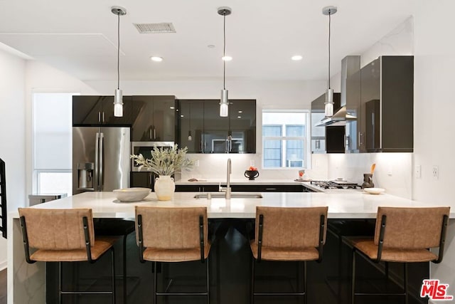 kitchen with hanging light fixtures, sink, stainless steel refrigerator with ice dispenser, a kitchen bar, and kitchen peninsula