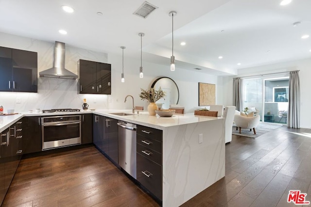 kitchen with pendant lighting, sink, wall chimney exhaust hood, dark hardwood / wood-style flooring, and stainless steel appliances