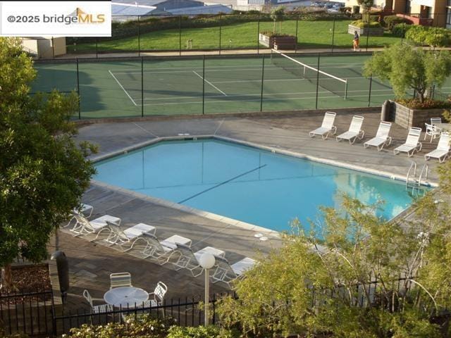 view of swimming pool featuring tennis court