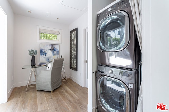 clothes washing area featuring light hardwood / wood-style floors and stacked washer and clothes dryer