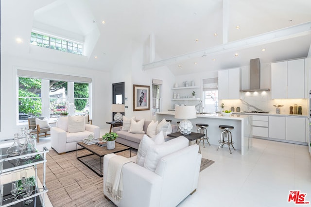 living room with beam ceiling, high vaulted ceiling, and sink