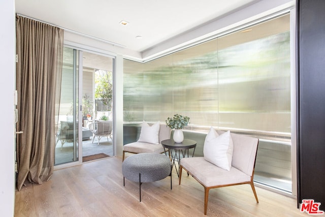 sitting room with light wood-type flooring and a wall of windows