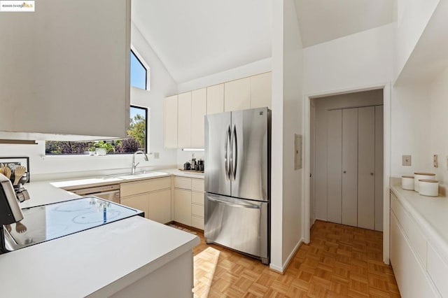 kitchen featuring high vaulted ceiling, light parquet floors, sink, cream cabinetry, and stainless steel refrigerator