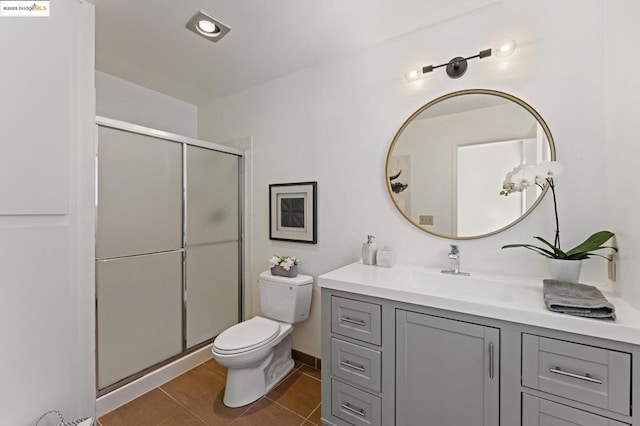 bathroom with tile patterned flooring, vanity, toilet, and a shower with door