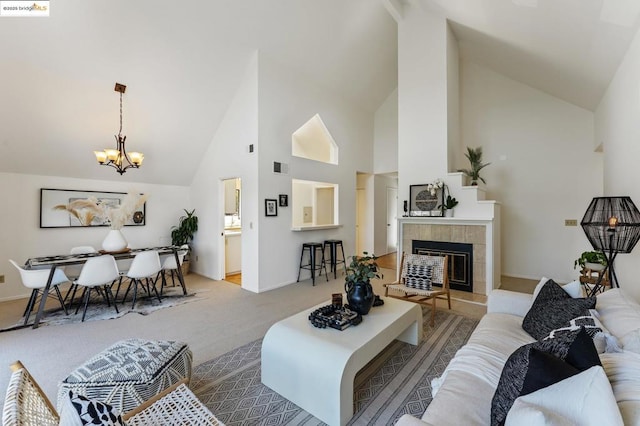 living room featuring a chandelier, light colored carpet, high vaulted ceiling, and a tiled fireplace