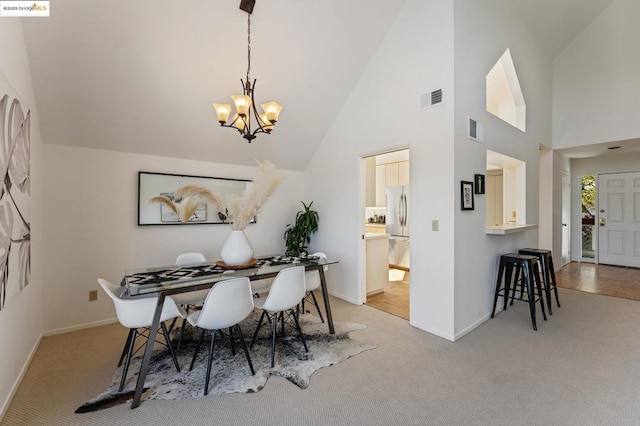 carpeted dining space with a notable chandelier and high vaulted ceiling